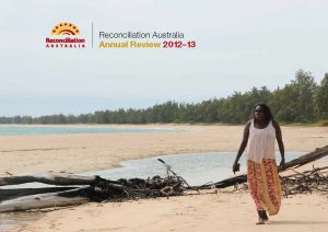 Cover of Reconciliation Australia Annual Review 2012-2013. Image shows an Indigenous woman walking along the sand with water and trees in the background