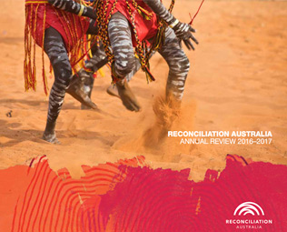 Cover of Reconciliation Australia Annual Review 2016-2017. Image shows the legs of two Indigenous people, painted and dressed and traditional clothes, dancing in the sand.