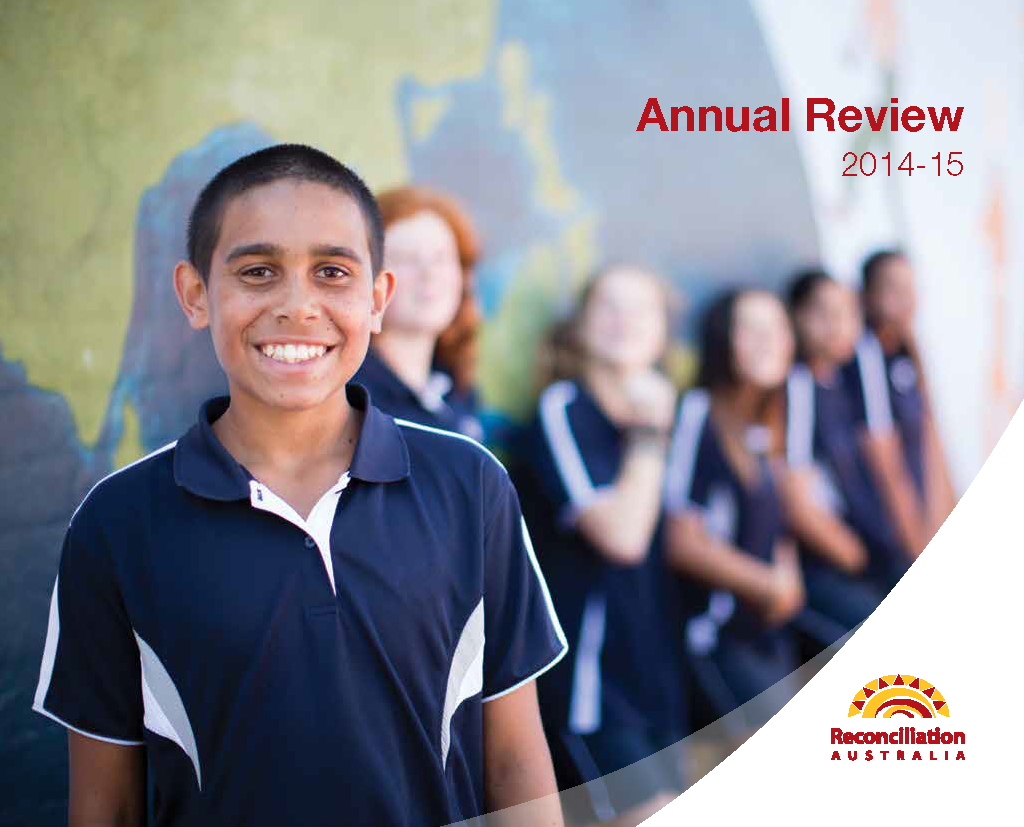 Cover of the Annual Review 2014-15. Image shows a young boy smiling into the camera wearing a blue and white school uniform, with his classmates blurred out in the background.