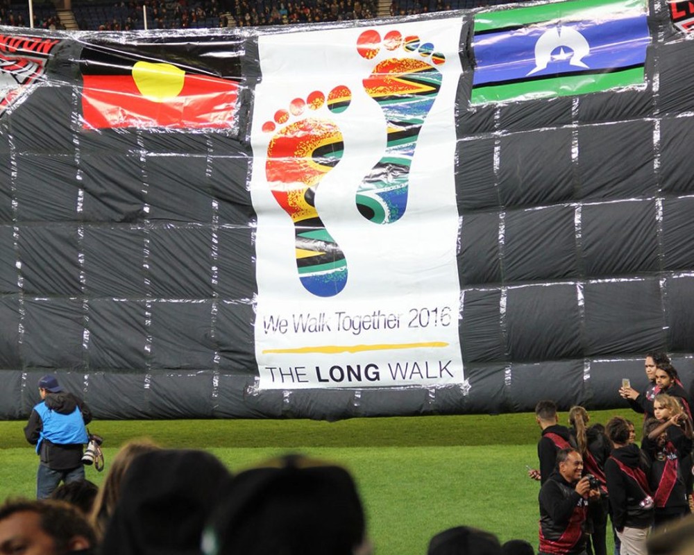 Large banner with Aboriginal and Torres Strait Islander flags at The Long Walk event.
