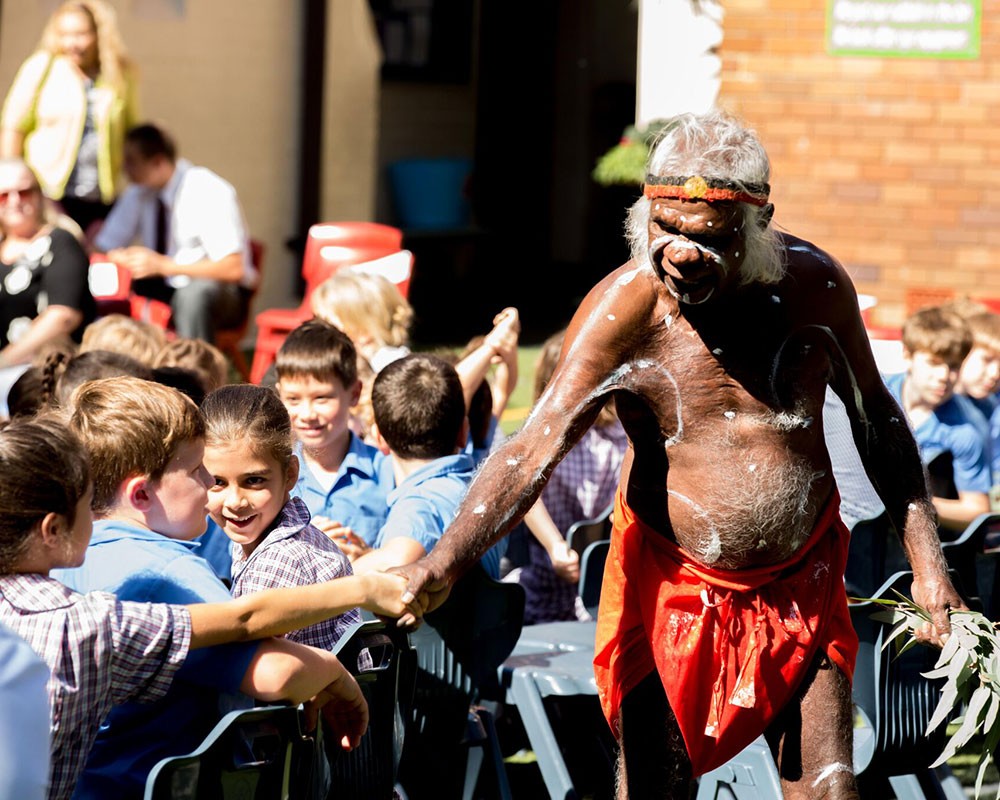 Child and Aboriginal Elder shaking hands at a cultural ceremony