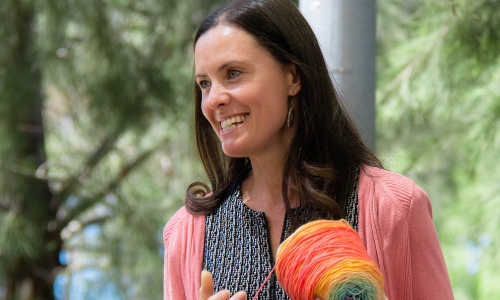 A Narragunnawali staff member smiles, holding a ball of yarn.