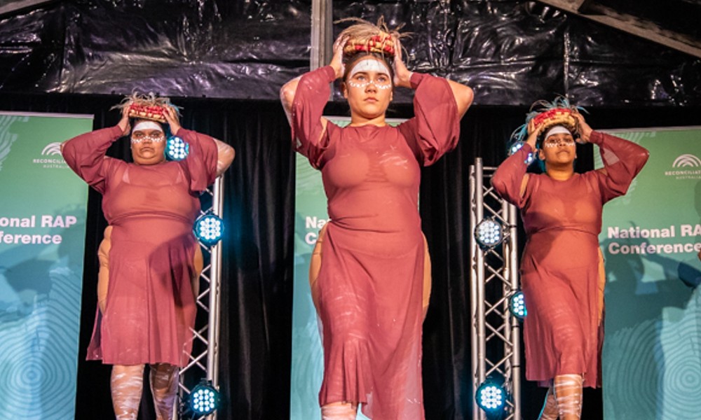 Three of the Brolga dancers perform on stage at the 2022 RAP Conference Welcome event