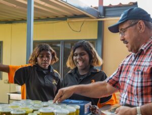 A man buys bush balm from two young students