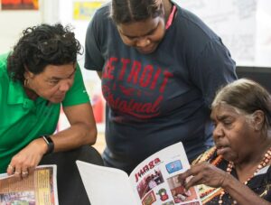 Three women look at an educational language booklet