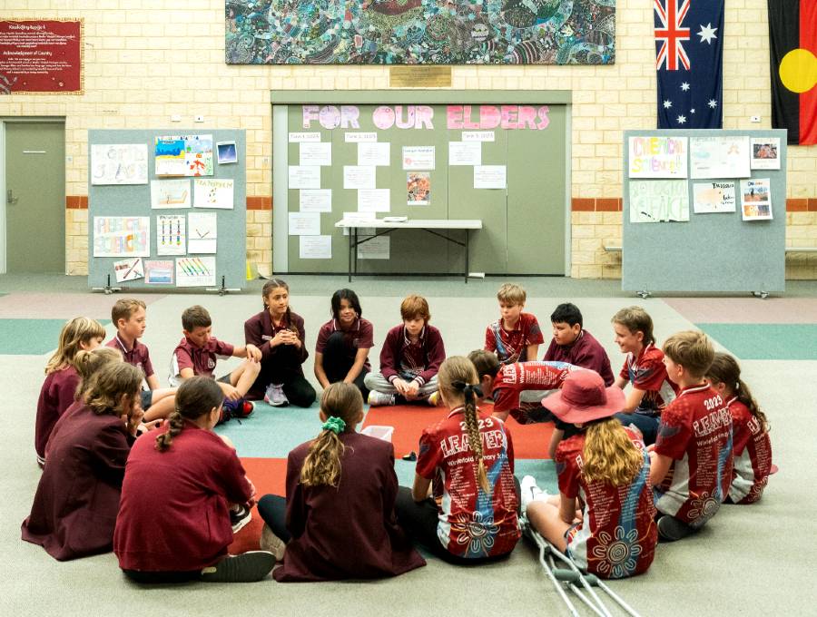 Group of children sitting on the floor in a large room at school