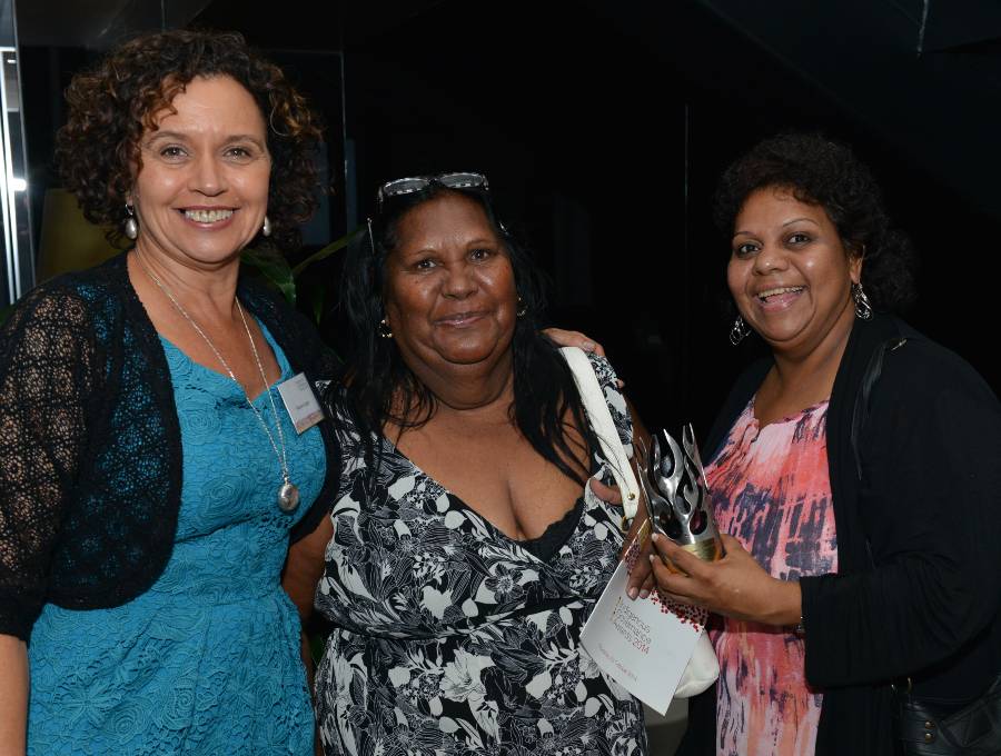 Three ladies stand smiling for a photo