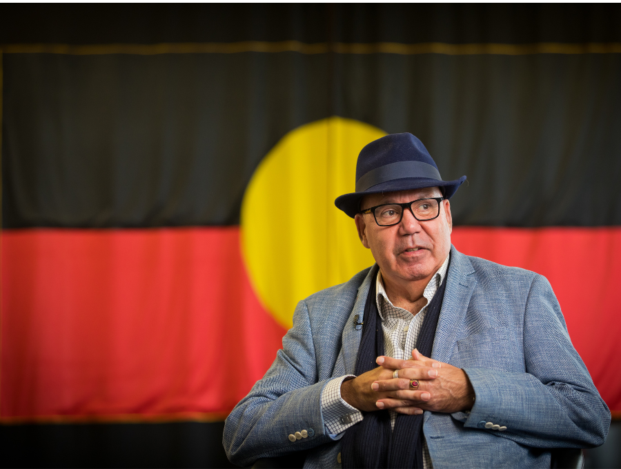 Man in hat in front of Aboriginal flag