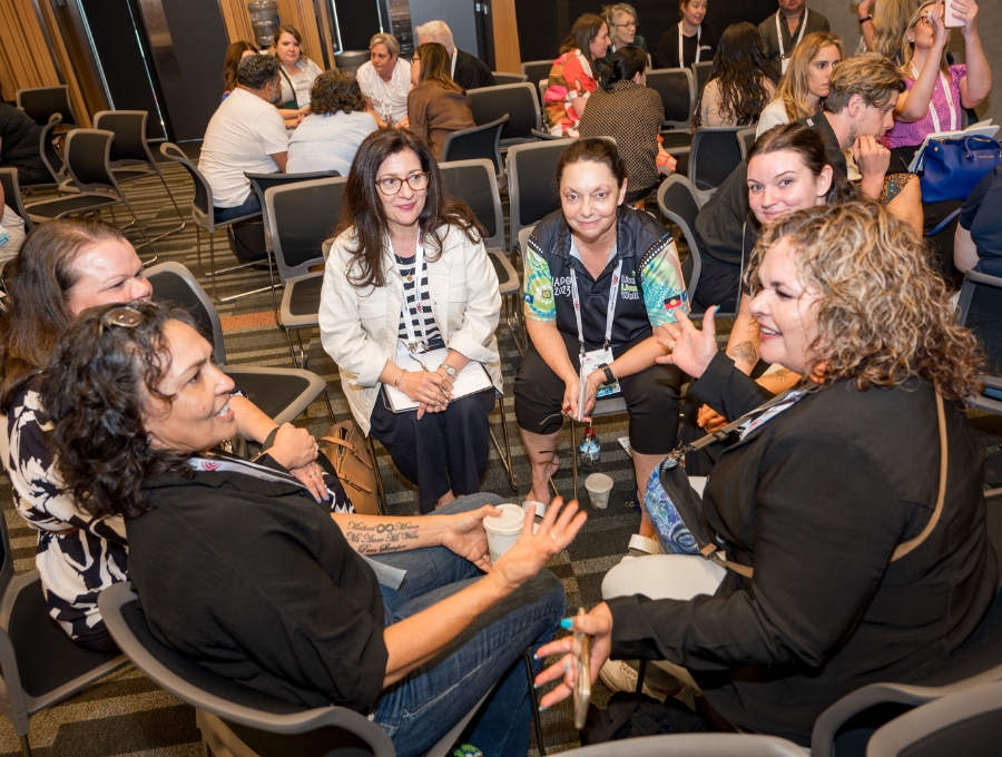 A group of people chat animatedly in a conference setting.