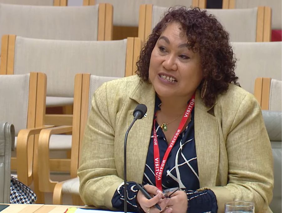 A woman sits in a parliamentary senate inquiry hearing, answering a question.