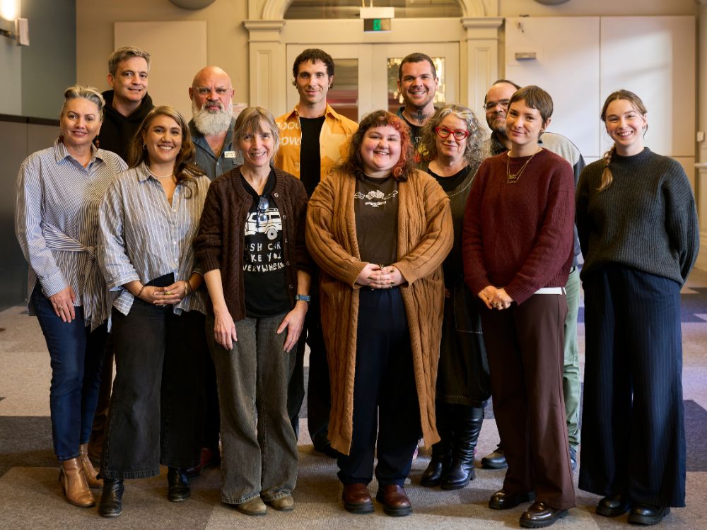 A group of people standing in a library foyer, smiling to camera.