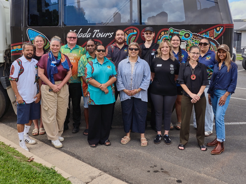 A group of people standing in front of a large offroader bus with the words 'Yalada Tours' and a big piece of Aboriginal artwork on the side.
