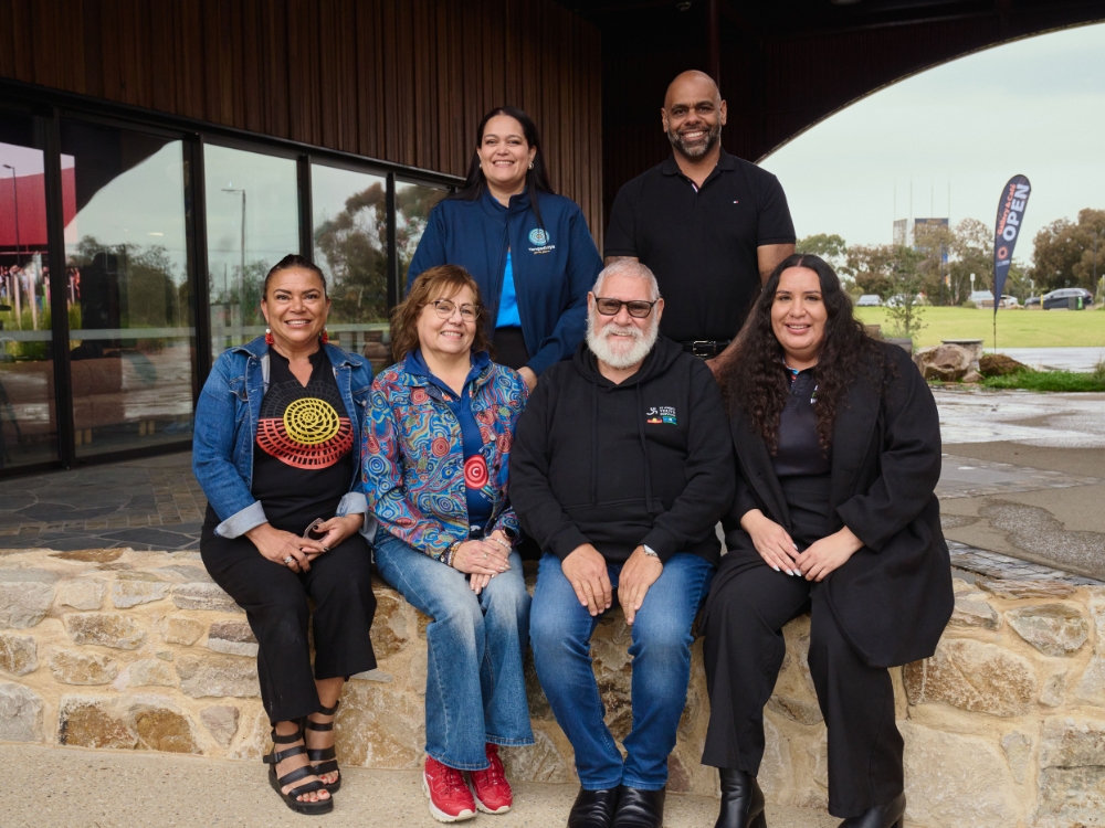 Group of people - four sitting on a low stone wall in front, two standing behind.