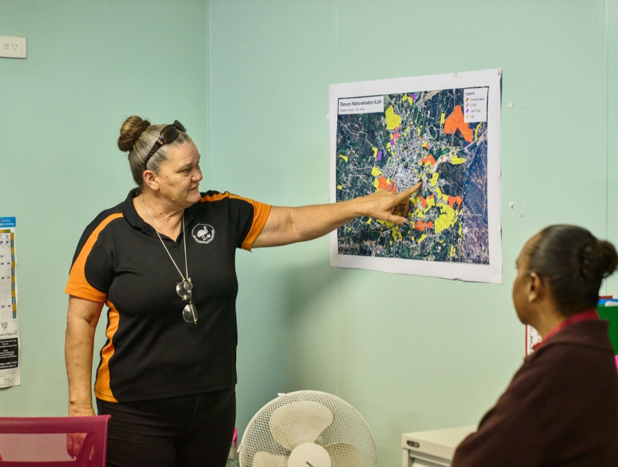 A woman points at a map on the wall.